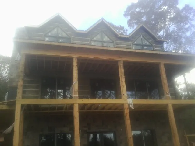 Dormers and porch framing on a large log home under construction — Roof Coating work by our crew in Amelia Court House