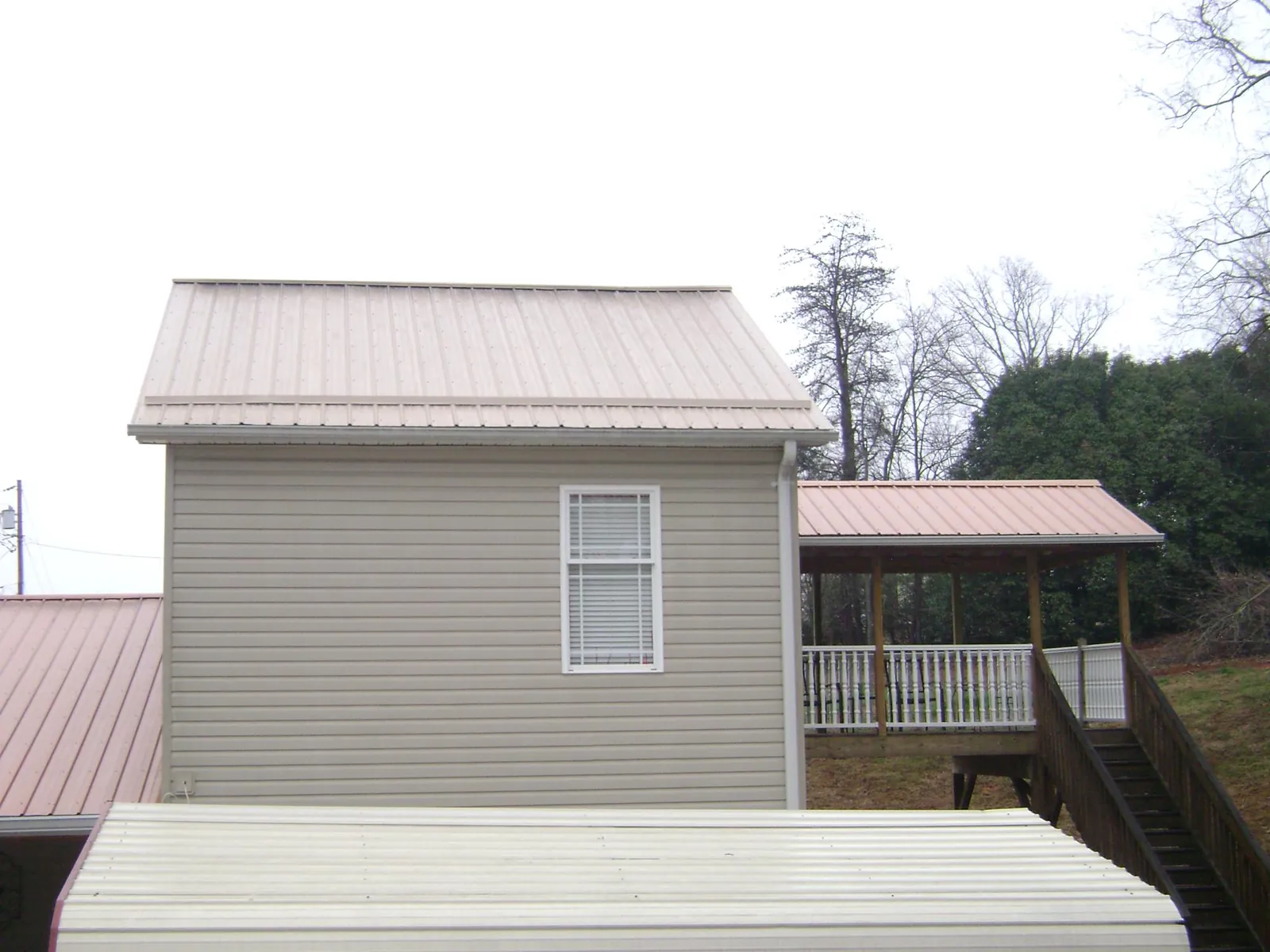 Tan metal roofs on a two story addition and attached porch, from a Roof Replacement job in Amelia Court House