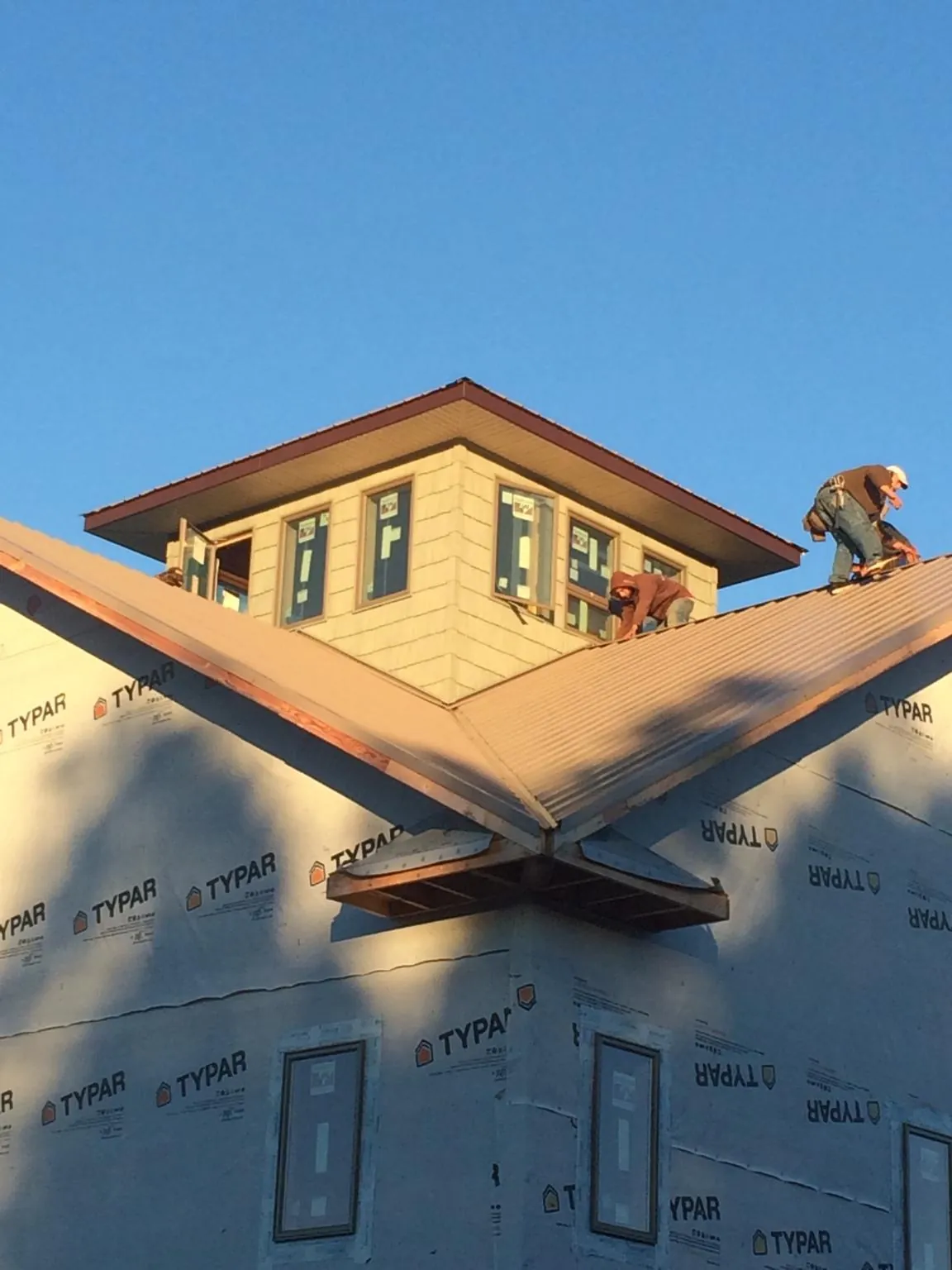 Roofers working around a rooftop cupola on a new metal roof at sunset — Roof Waterproofing in Amelia Court House by Roofing Brothers